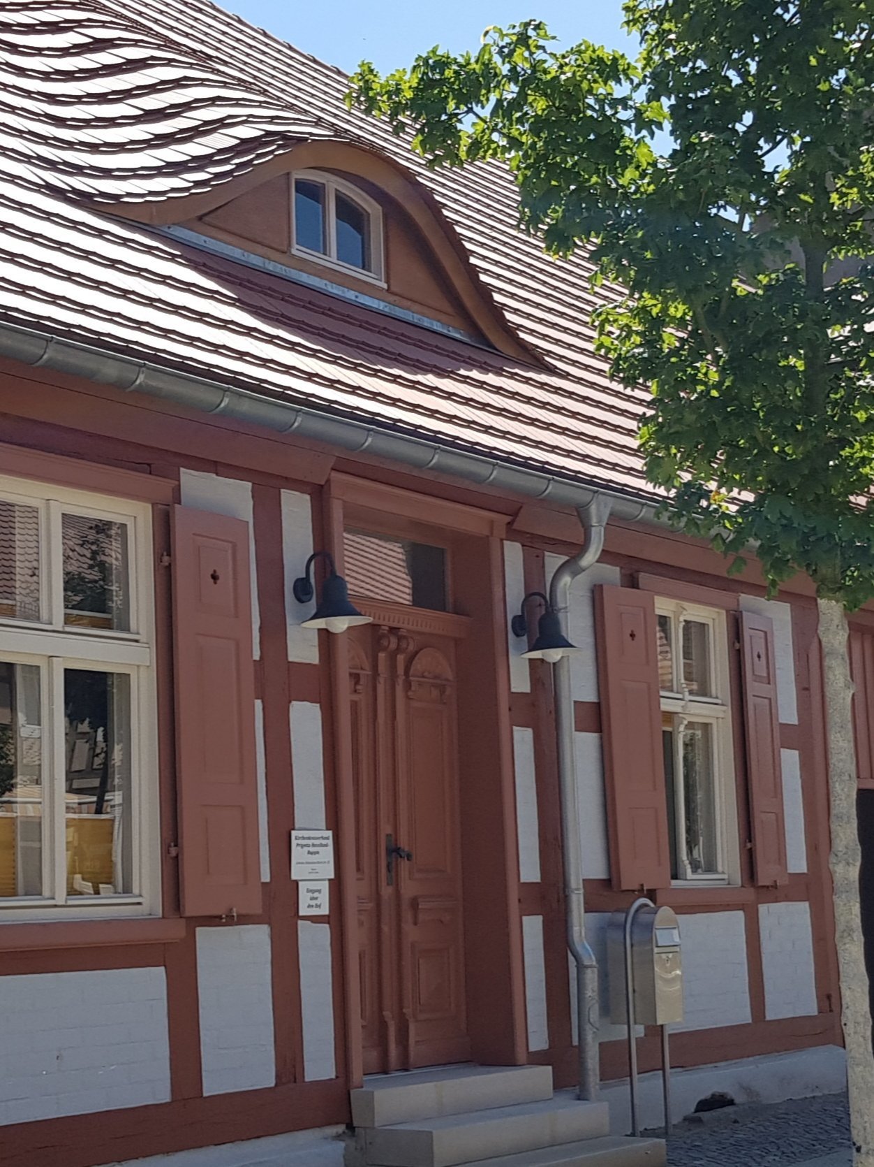 Historisches Fachwerkhaus mit geschwungenem Dach, wahrscheinlich das Pfarrhaus.